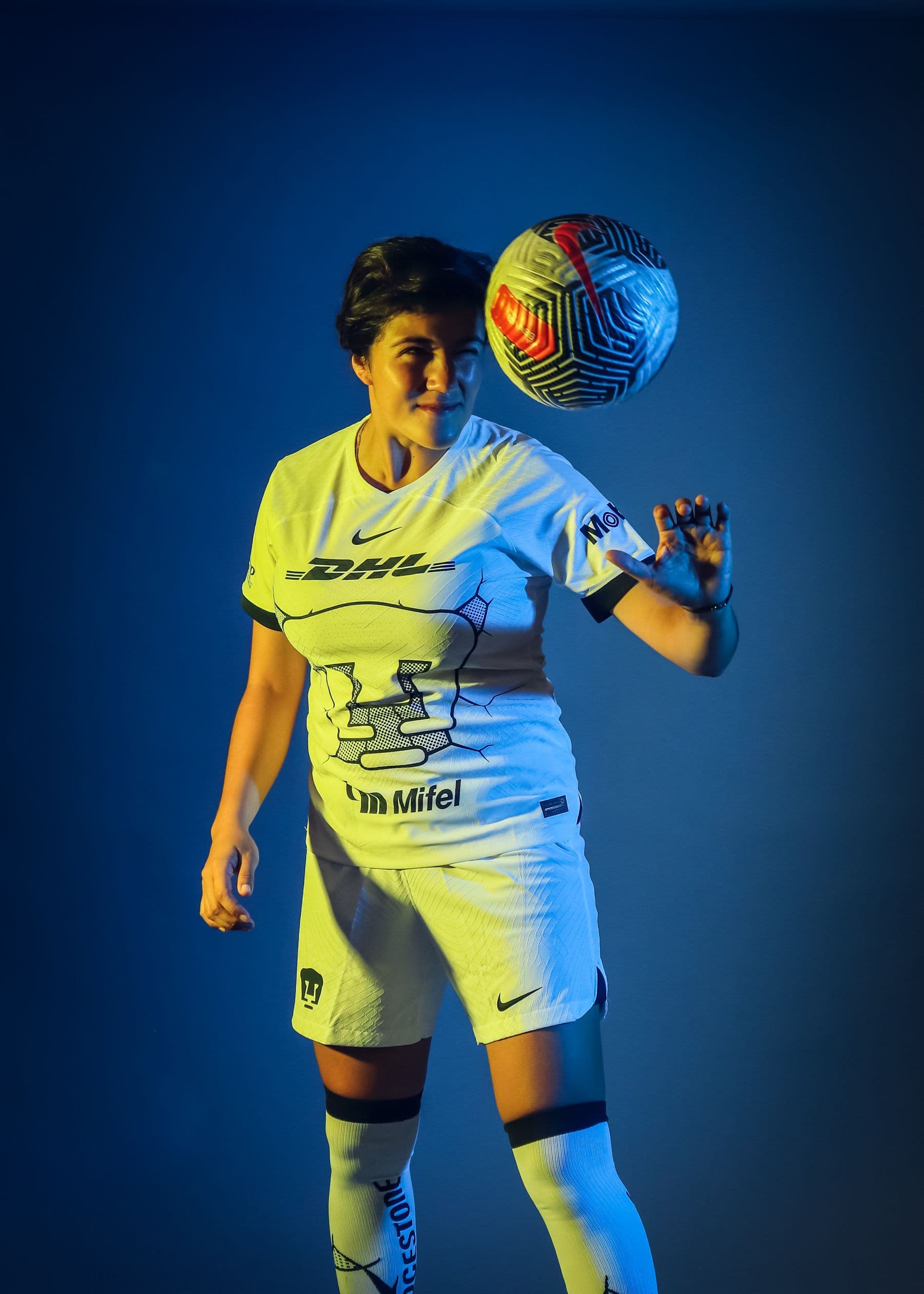 Woman footballer balancing a ball in a studio portrait